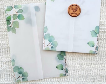 Puede incluir: Dos sobres blancos con un diseño de acuarela de hojas verdes. El sobre superior tiene un sello de cera marrón con un diseño floral.