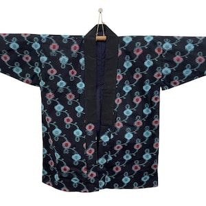 May include: A dark navy blue kimono-style jacket with a floral pattern in light blue and red. The jacket has a black collar and trim, and is hanging from a wooden hanger.