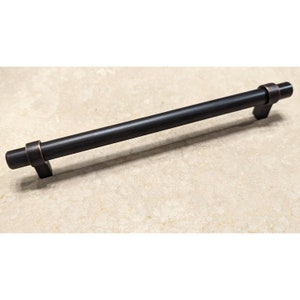 May include: A black metal cabinet pull with a brushed finish and copper accents. The pull is approximately 5 inches long.