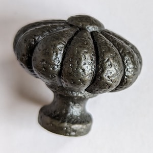 May include: A dark gray cast iron cabinet knob with a textured, bulbous design. The knob has a rounded top and a short, cylindrical base.