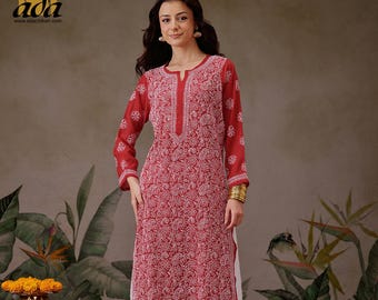 Puede incluir: Una kurta roja de manga larga con bordados blancos. La kurta tiene cuello en V y está hecha de una tela ligera. La modelo lleva la kurta con pantalones blancos.