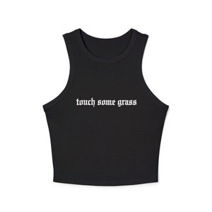 Puede incluir: Top corto negro sin mangas con el texto "touch some grass" en fuente gótica blanca.