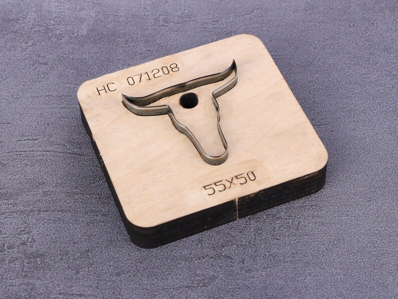 May include: A wooden die-cutting template shaped like a bull's head with horns. The template is labeled "HC 071208" and "55x50".