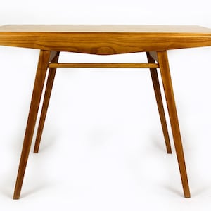 Può includere: Un tavolo in legno con un piano rettangolare e quattro gambe. Il tavolo è in legno marrone chiaro e ha un design semplice e moderno.