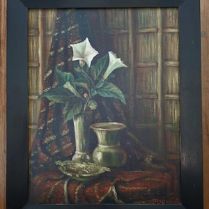 May include: An oil painting in a black frame depicting a still life with two white trumpet-shaped flowers in a tall vase, a shorter rounded vase, and a small bowl on a dark red patterned cloth, set against a background of vertical wooden panels.