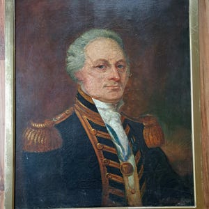 May include: A portrait painting of a man in a navy blue military uniform with gold trim and a medal. The man has white hair and a serious expression. The painting is framed in a gold frame and has a label at the bottom that reads "ADMIRAL SIR W PARKER BART K.C.B."