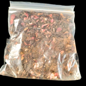 May include: A clear plastic bag filled with a mix of dried herbs and flower petals. The contents appear to be a blend of dark green, brown, and reddish-pink elements, suggesting a tea or herbal mixture. The bag is sealed with a zip closure.