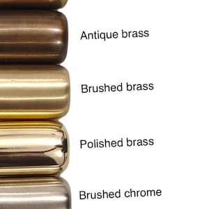 May include: A vertical row of 11 cylindrical metal samples in different finishes, including brushed antique brass, antique black, blackened brass, raw brass, antique brass, brushed brass, polished brass, brushed chrome, polished chrome, matte black, and matte white.