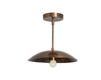 May include: A bronze-colored pendant light fixture with a rounded shade and a single bulb. The fixture has a stem and a circular ceiling mount. The light is suspended from the ceiling, offering a warm, ambient glow.