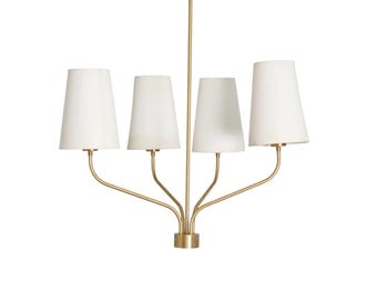 May include: A gold-toned chandelier with four white lampshades. The lampshades are conical and taper towards the top. The fixture has a central stem and curved arms extending to hold the lamps.