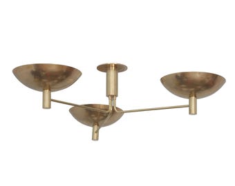 May include: A brass ceiling light fixture featuring three bowl-shaped shades attached to a central stem. The metal has a warm, metallic finish, and the design includes thin arms extending from the center to support each individual bowl.