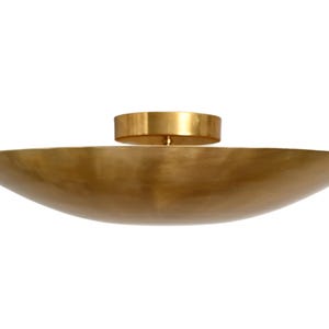 May include: A gold-toned ceiling light fixture with a wide, shallow, bowl-shaped shade.