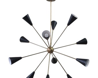 May include: A mid-century modern chandelier with a brass finish and black cone-shaped shades. The light fixture has multiple arms extending from a central sphere, each holding a light. The design is symmetrical and geometric.
