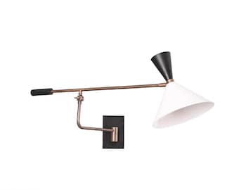 May include: A modern wall-mounted lamp with a black and white conical shade. The lamp features a bronze-colored arm and a black rectangular base. The lamp's design is sleek and minimalist, suitable for various interior styles.