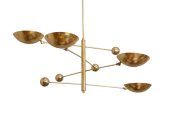May include: A modern, brass-toned chandelier with six bowl-shaped light fixtures. The fixtures are arranged on horizontal arms extending from a central vertical rod, with spherical accents. The design is minimalist and elegant.