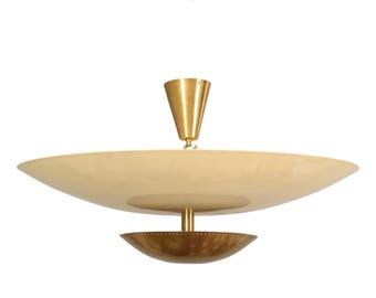 May include: A ceiling pendant light fixture featuring a large, shallow, off-white saucer-shaped shade suspended from a conical brass canopy. A smaller, perforated brass bowl is attached beneath the main shade by a central brass rod.