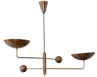 May include: A brass chandelier with three lights. The chandelier has a central stem with three arms extending out. Each arm has a round light fixture and a bowl-shaped shade. The chandelier is in a modern style.