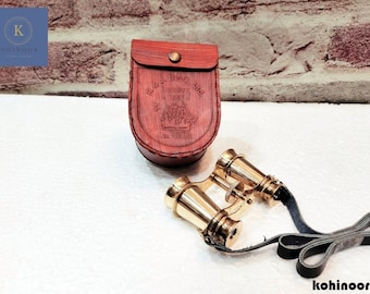 Könnte beinhalten: Messing-Fernglas mit einer Ledertragetasche. Die Tasche hat ein geprägtes Design mit dem Text "Royal Bell London 1847" und einer Krone.