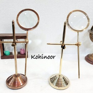 May include: Two brass magnifying glasses on stands. Each stand has a round base and a crossbar with a magnifying glass attached to it. The magnifying glasses are clear and have a brass frame.