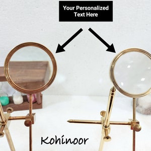 May include: Two gold magnifying glasses on stands, with the text "Your Personalized Text Here" above them. The magnifying glasses are positioned so that the lenses are facing each other. The text "Kohinoor" is visible below the magnifying glasses.