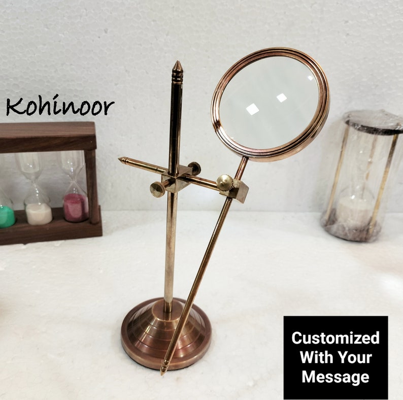 May include: A brass magnifying glass on a stand with a round base. The magnifying glass is adjustable and can be moved up and down. The stand is about 10 inches tall.