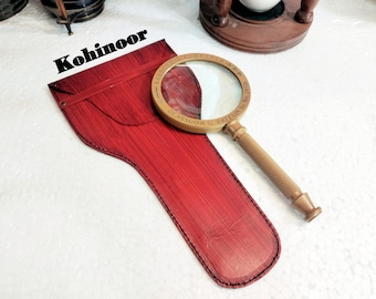 May include: A magnifying glass with a brass frame and wooden handle. The glass is in a red leather case with the word "Kohinoor" printed on it. The magnifying glass has the inscription "Glasgow G Britain No 323" on the frame.
