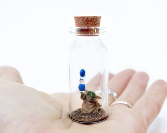 Carino Baby Yoda Grogu in miniatura in una bottiglia, usando la forza per far levitare Macaron - Regalo divertente mandaloriano di Star Wars fatto a mano per i geek della fantascienza