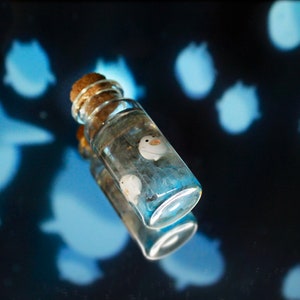 Unique handcrafted depiction of Warawara creatures from The Boy and the Heron in a sky-colored resin bottle by Miniatures Guild