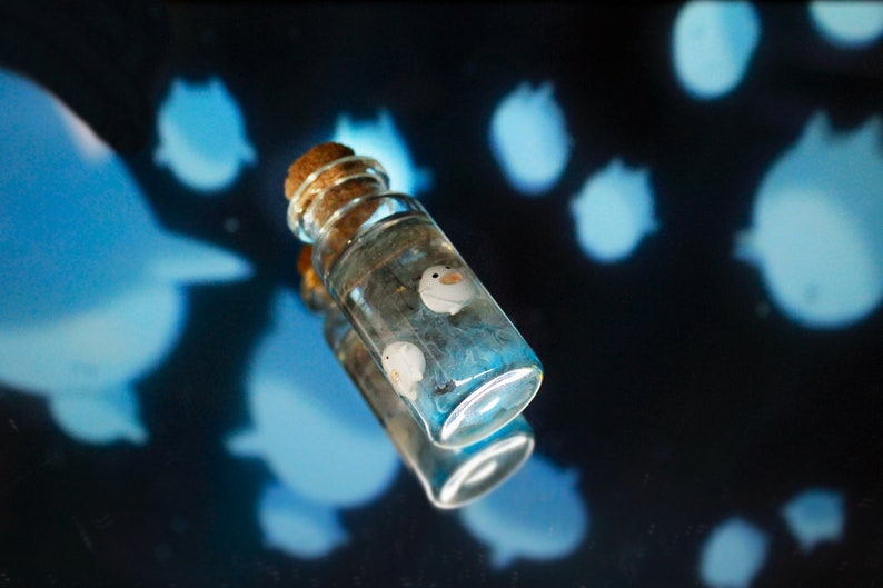 Unique handcrafted depiction of Warawara creatures from The Boy and the Heron in a sky-colored resin bottle by Miniatures Guild