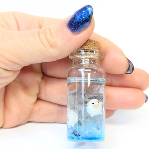 Hand holding Handcrafted miniature of Mini Warawara creatures in sky-colored resin, inspired by Studio Ghibli's 'The Boy and the Heron' by Miniatures Guild shop on Etsy