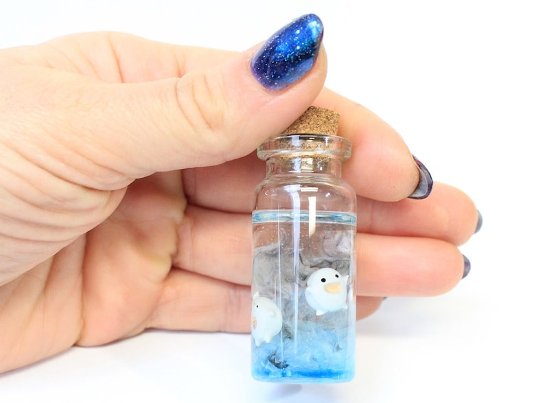 Hand holding Handcrafted miniature of Mini Warawara creatures in sky-colored resin, inspired by Studio Ghibli's 'The Boy and the Heron' by Miniatures Guild shop on Etsy