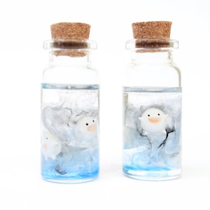 Close-up of delicate handmde Warawara creatures floating in a resin bottle resembling a serene sky, Studio Ghibli art inspired of The Boy and the Heron