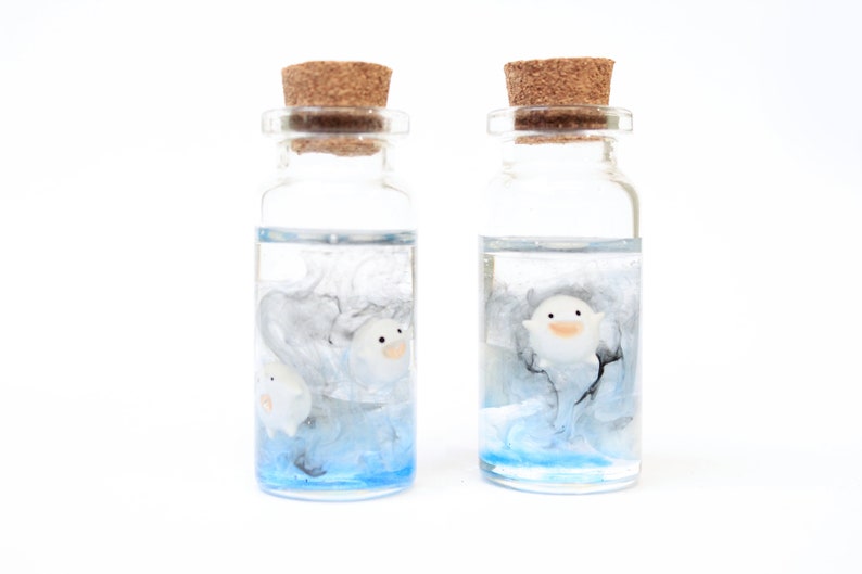 Close-up of delicate handmde Warawara creatures floating in a resin bottle resembling a serene sky, Studio Ghibli art inspired of The Boy and the Heron
