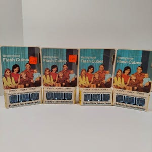 May include: Four packs of Westinghouse Flash Cubes, each containing three cubes. The packs are yellow and blue with a picture of a family on the front. The text on the front reads "Westinghouse Flash Cubes" and "3 Cubes/12 Color Balanced Flashes".