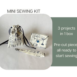 May include: A mini sewing kit featuring a drawstring pouch, a small folded wallet with a blue button, and a wrist strap with a metal clasp. The fabric is cream-colored with a black vintage sewing pattern print. Text reads: MINI SEWING KIT, 3 projects in 1 box, Pre-cut pieces all ready to start sewing.