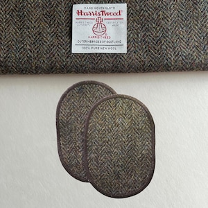 Pode incluir: Duas bases ovais em tweed Harris com bordas marrons, apresentadas com um pedaço de tecido a condizer. A etiqueta Harris Tweed é visível, indicando a origem do tecido das Hébridas Exteriores da Escócia e a sua composição de 100% pura lã virgem.