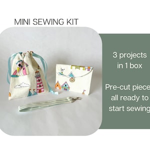 May include: A mini sewing kit featuring a drawstring pouch, a small envelope-style case, and a striped wrist strap. The fabric has a colorful lighthouse and house print. Text reads: MINI SEWING KIT, 3 projects in 1 box, Pre-cut pieces all ready to start sewing.