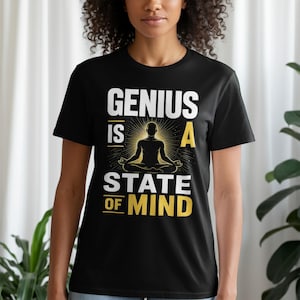 May include: A black short-sleeve t-shirt featuring a graphic print with the text "GENIUS IS A STATE OF MIND" in white and yellow. The design includes a central silhouette of a person in a seated meditation pose surrounded by yellow sunburst lines.