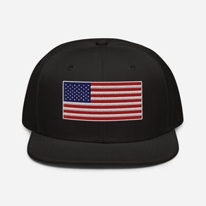 Puede incluir: Gorra de béisbol negra con una bandera americana bordada. La bandera tiene rayas rojas y blancas y una sección azul con estrellas blancas. La gorra tiene una visera plana y una corona estructurada.