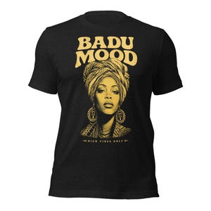May include: Black t-shirt with a gold graphic of a woman in a turban and earrings. The words "BADU MOOD" are above the image, with "HIGH VIBES ONLY" below. The design is in gold.