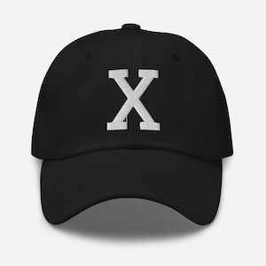 May include: A black baseball cap with a white embroidered letter X on the front.
