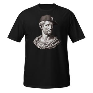 May include: Black t-shirt with a graphic of a classical bust wearing a baseball cap with a white "NY" logo. The bust is in grey and white, contrasting with the black of the shirt. A unique fusion of classical and modern styles.