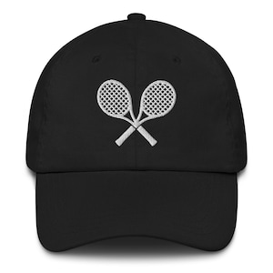 May include: Black baseball cap with a curved brim. The cap features a white embroidered design of two crossed tennis rackets on the front. The cap has a structured fit and a top button.