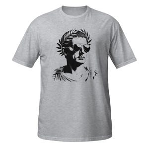 May include: A gray t-shirt with a black and white illustration of a person wearing a laurel wreath and sunglasses. The person is depicted in a profile view.