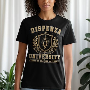 May include: A black short-sleeved t-shirt featuring a gold and white graphic print. The design includes the text DISPENZA UNIVERSITY and SCHOOL OF QUANTUM COHERENCE, centered around a shield emblem with a central symbol and laurel leaf accents.
