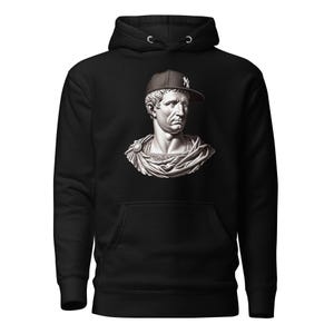 May include: Black hoodie featuring a white bust of a man wearing a black and white baseball cap. The cap has a white logo on it.