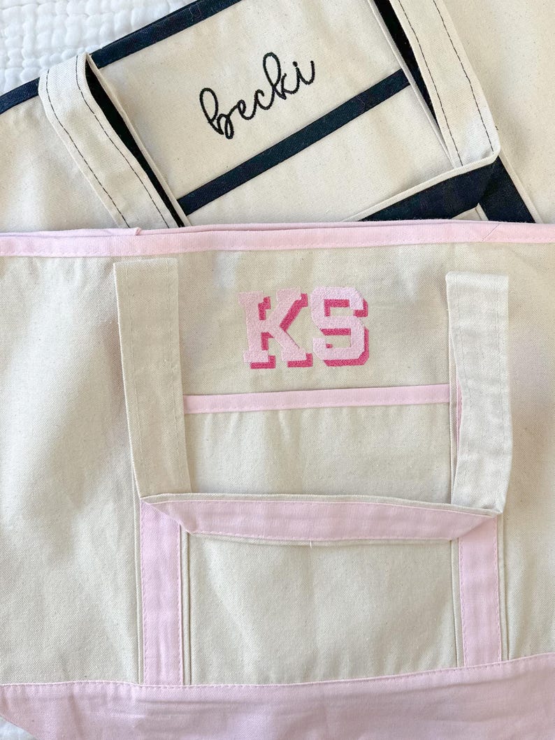 Może przedstawiać: Beżowa torba typu tote z r&oacute;żowym wykończeniem i haftowanym r&oacute;żowym monogramem "KS" z przodu.