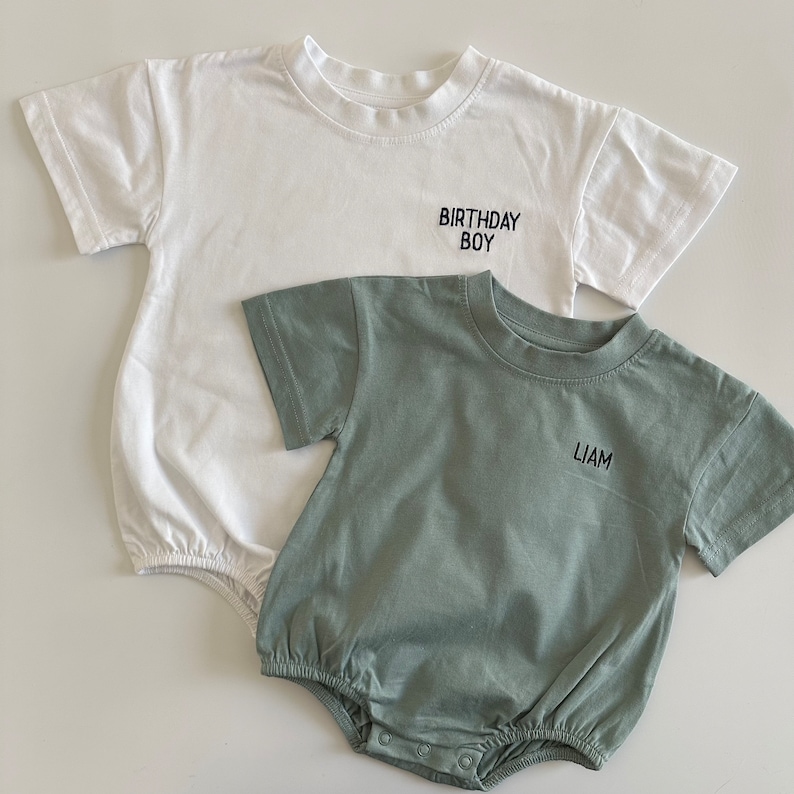 May include: Two short-sleeved shirts, one white and one green. The white shirt has the text "Birthday Boy" embroidered on the front. The green shirt has the name "Liam" embroidered on the front.