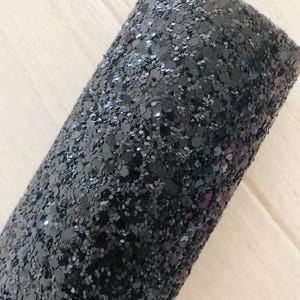 May include: Black glitter fabric with a fine, sparkly texture. The fabric is rolled up and shows the glitter texture.