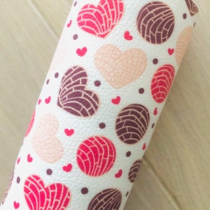 May include: White fabric with a repeating pattern of pink, red, and brown heart-shaped pastries with white polka dots.